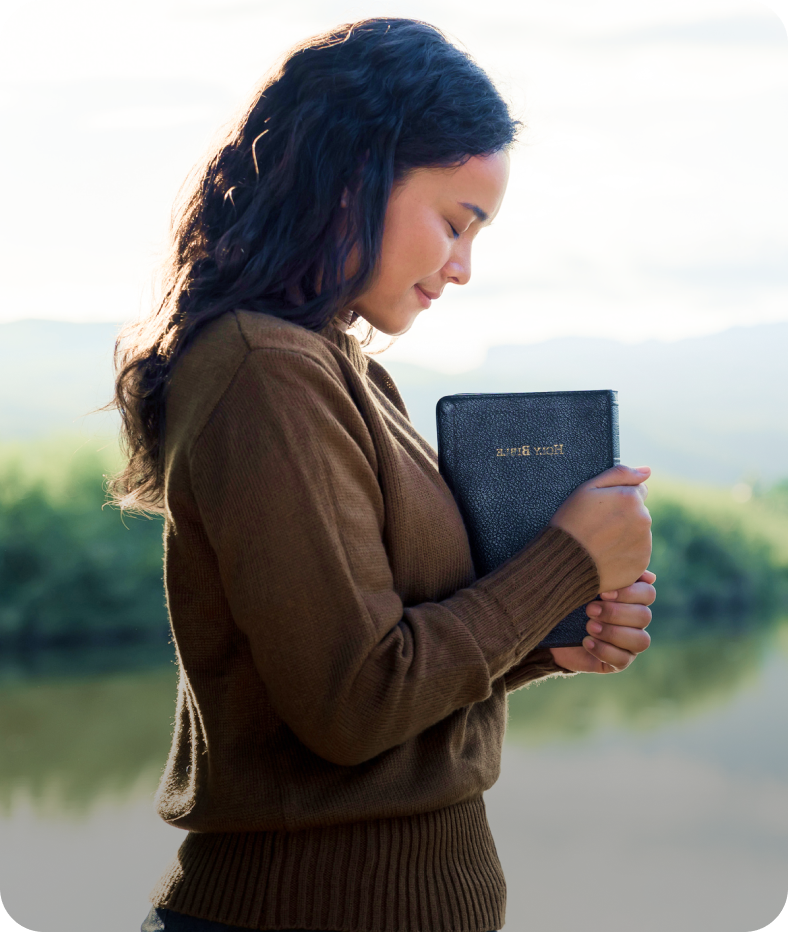 Woman holding a book near a lake.