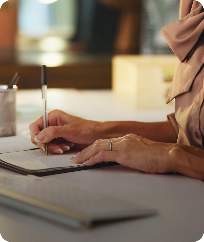 Person writing in notebook at a desk.