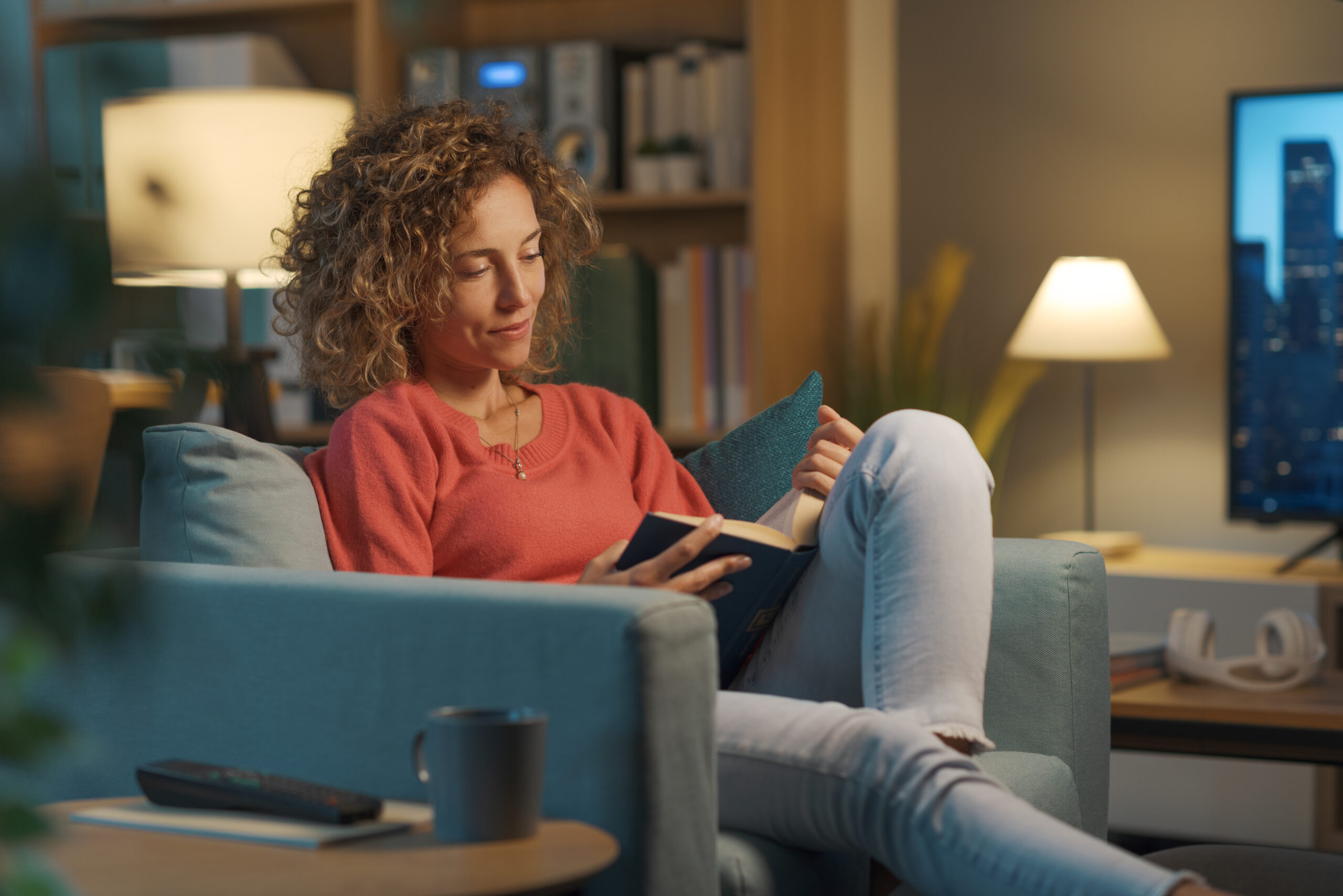 Woman reading a book on a sofa.