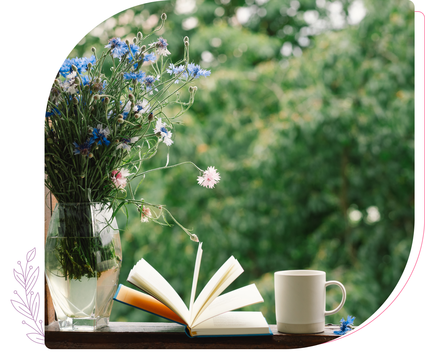 Open book, flowers, and mug by window.